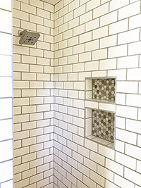 New shower with white subway tile and recessed shelves after master bathroom remodel