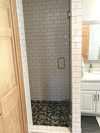 Enclosed shower with white subway tile and glass door after master bathroom remodel