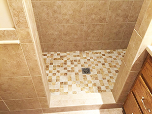 Bathroom shower walls and floor remodeled with large tan porcelain tiles and small mosaic tile in Rochester, MN